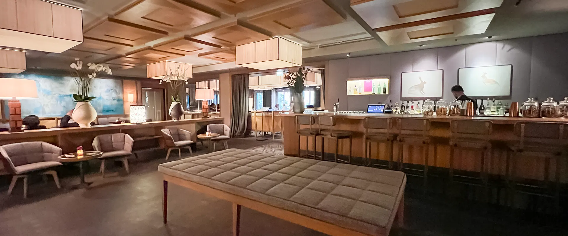 Eine geräumige Bar mit einer langen Theke aus Holz, gemütlichen Sofas und Sesseln sowie einer dekorativen Holzdecke.