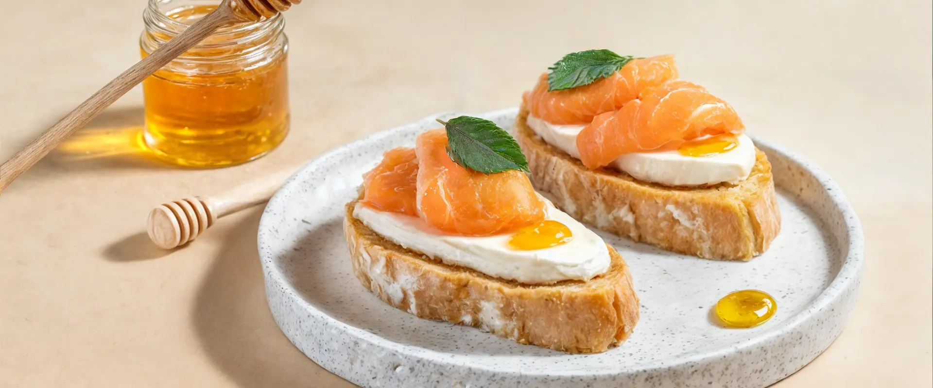 Platzhalter_1920x800 Zwei Brotscheiben, belegt mit Frischkäse, dünnen Scheiben Lachs und einem Hauch Honig, garniert mit einem frischen Blatt.